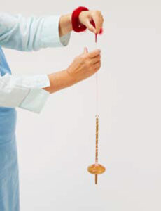 person spinning yarn on a drop spindle